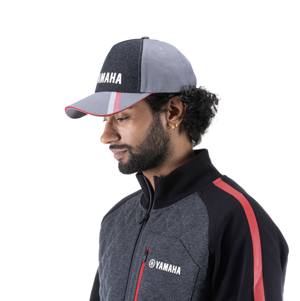 Man wearing grey Yamaha hat and jacket with red stripes.
