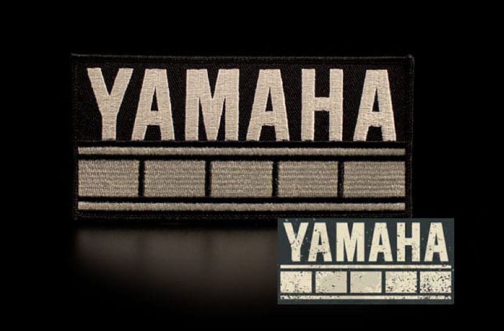 Beige Yamaha badge in all caps against a dark background.