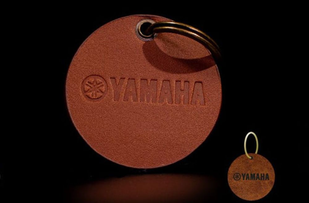a Yamaha tan leather keyring on a dark background.