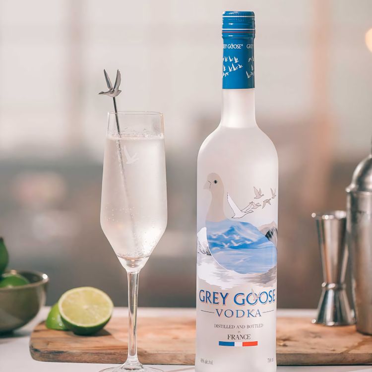 A frosted Grey Goose bottle and flute glass on a kitchen bar.