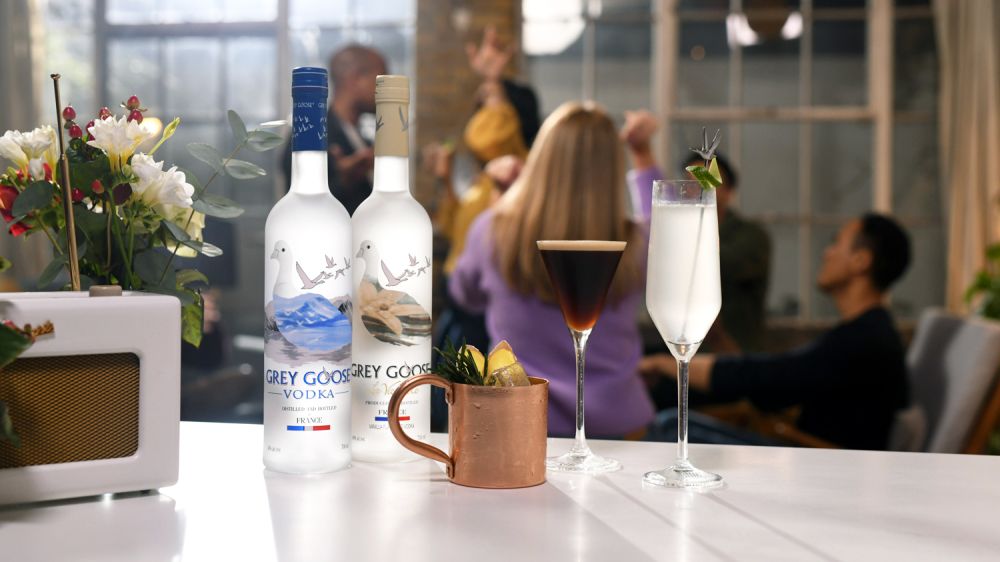 A couple of bottles of Grey Goose on a coffee bar next to an Espresso Martini and decorative copper mug.