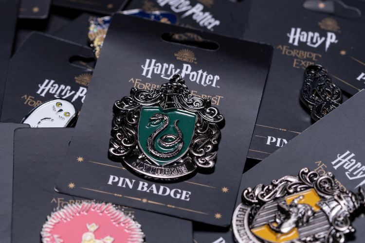 Various pin badges including Slytherin and the other houses.