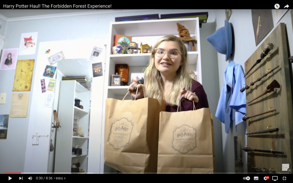 Screenshot of unboxing video with a lady holding up a Forbidden Forest paper bags.