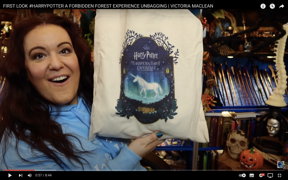Screenshot of unboxing video with a lady holding up a Forbidden Forest tote bag.