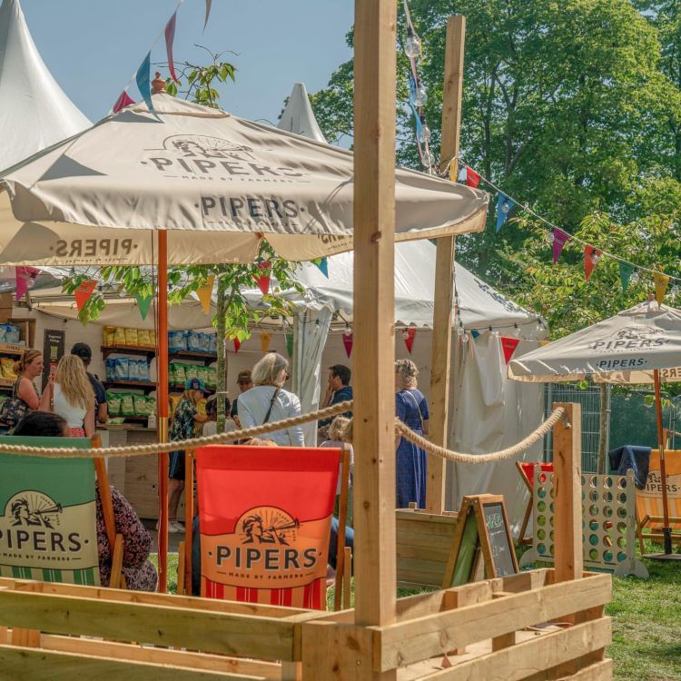 Pipers Crisps lined up in a marquee style tent with wooden crates.