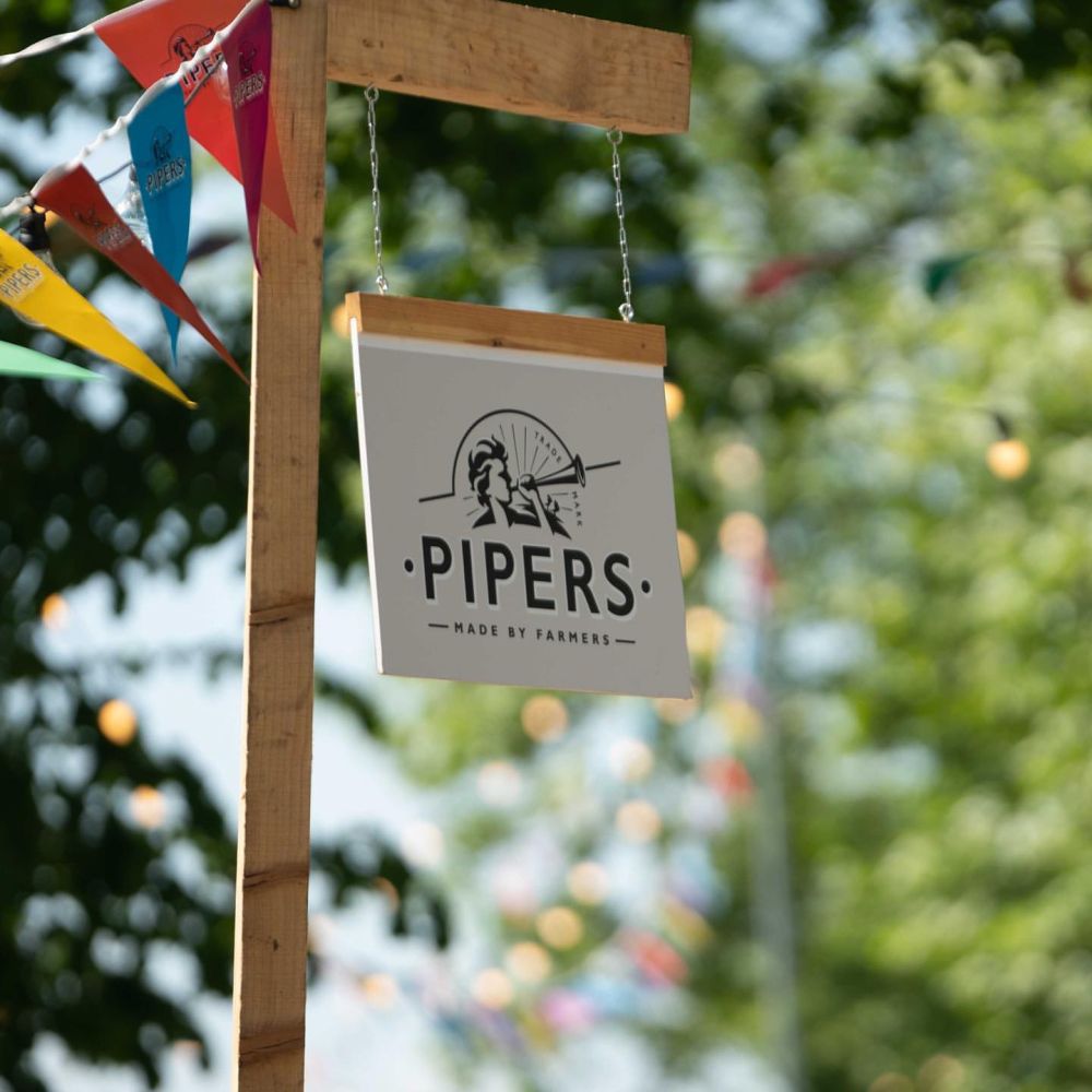 Pipers sign swinging on a wooden post with bunting.