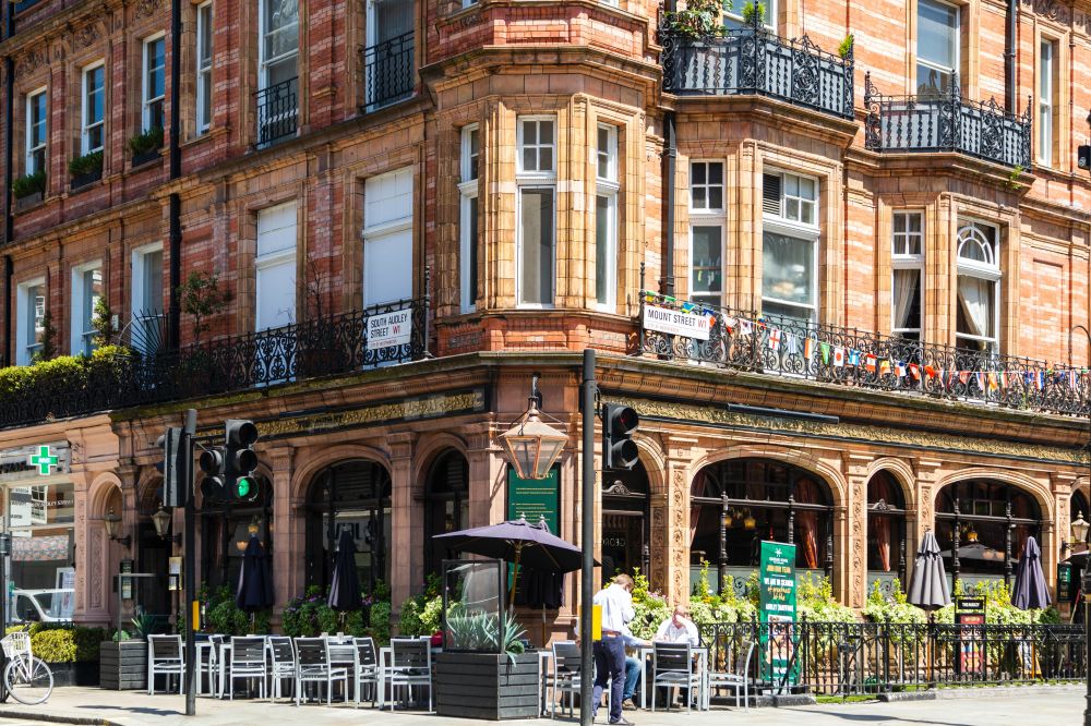 Corner of a street in Mount Street Printers, London, United Kingdom. There's a beautiful copper lamp on the corner, a pub with large glass windows, and Victorian flats above.