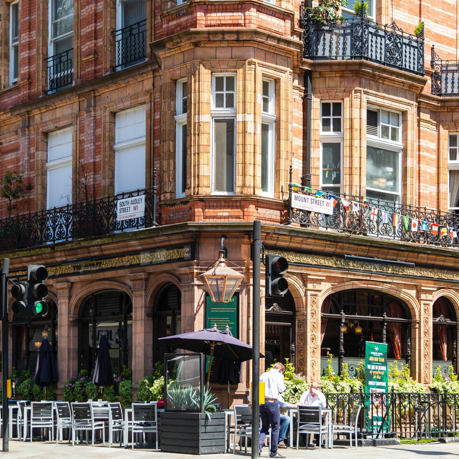 Corner of a street in Mount Street Printers, London, United Kingdom. There's a beautiful copper lamp on the corner, a pub with large glass windows, and Victorian flats above.