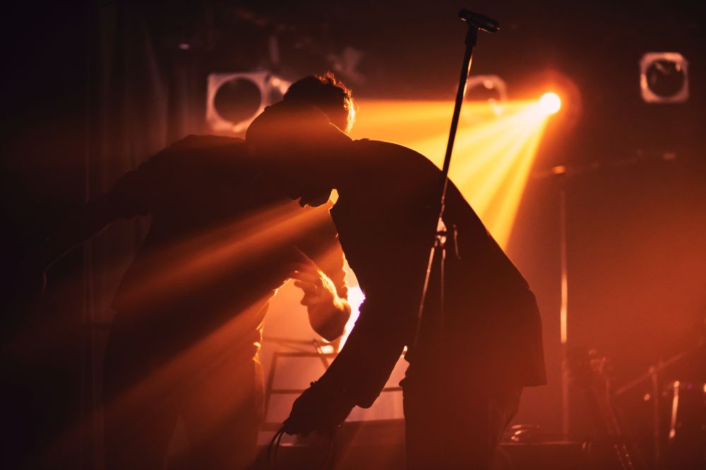 Musician setting up in low orange light with a mic in the foreground.