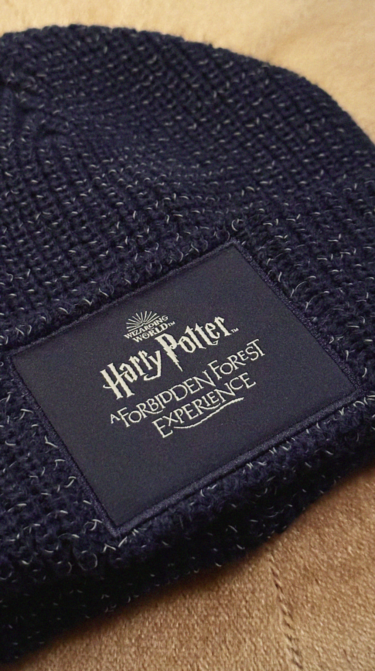 A knitted hat with a Forbidden Forest badge on the front.