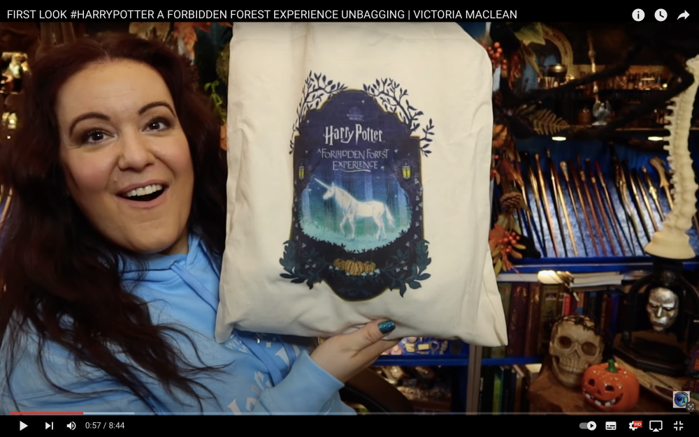 Screenshot of unboxing video with a lady holding up a Forbidden Forest tote bag.
