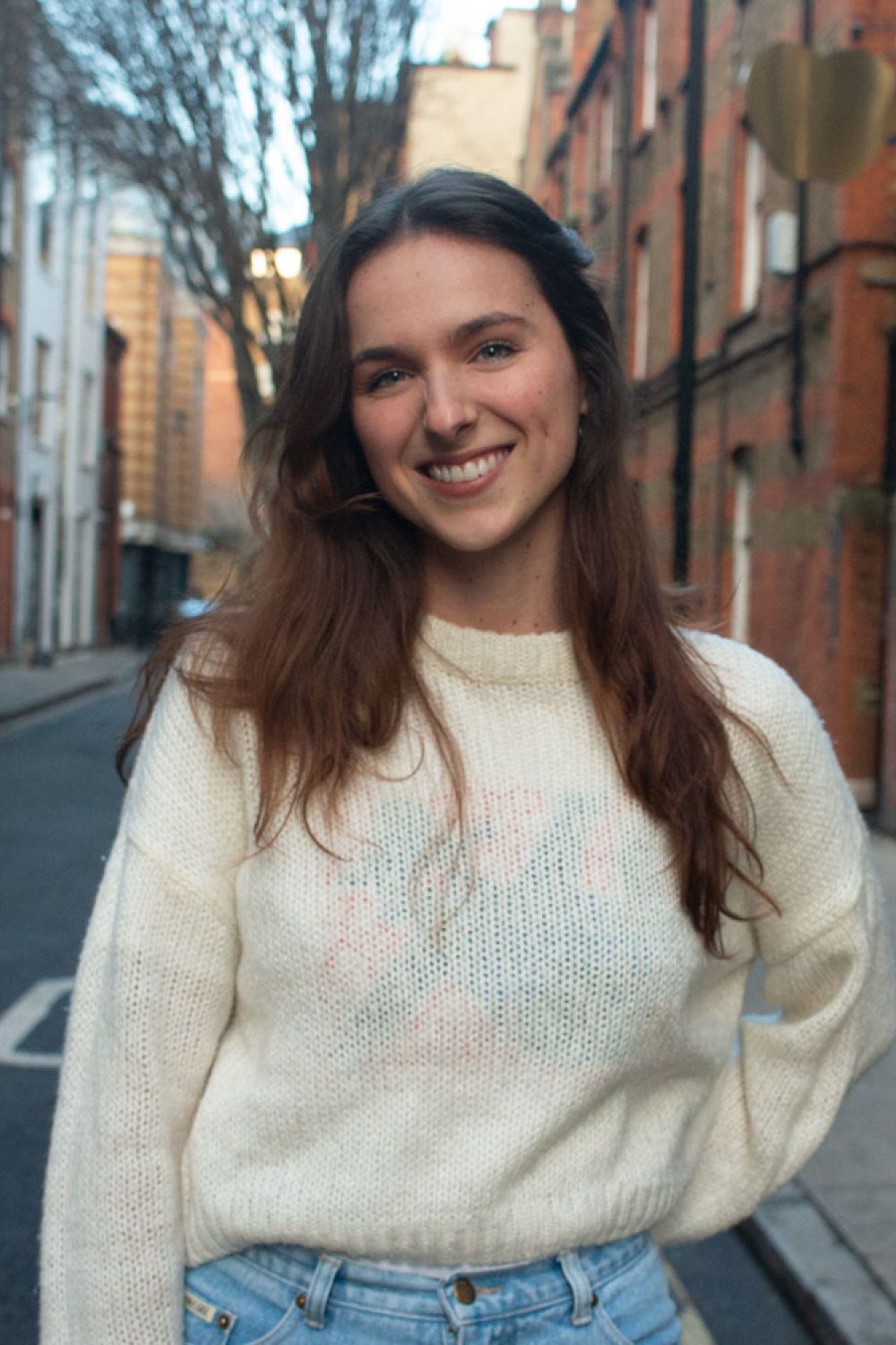 Gemma Brown smiling with a beige jumper and jeans outside the office in Macklin Street.